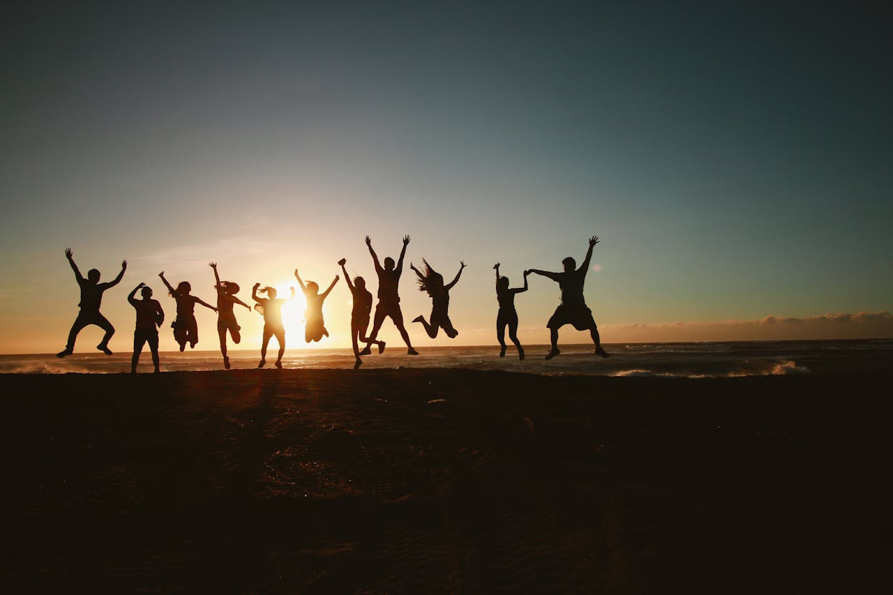 Groupe de collègues sautant de joie au coucher du soleil lors d’un team building